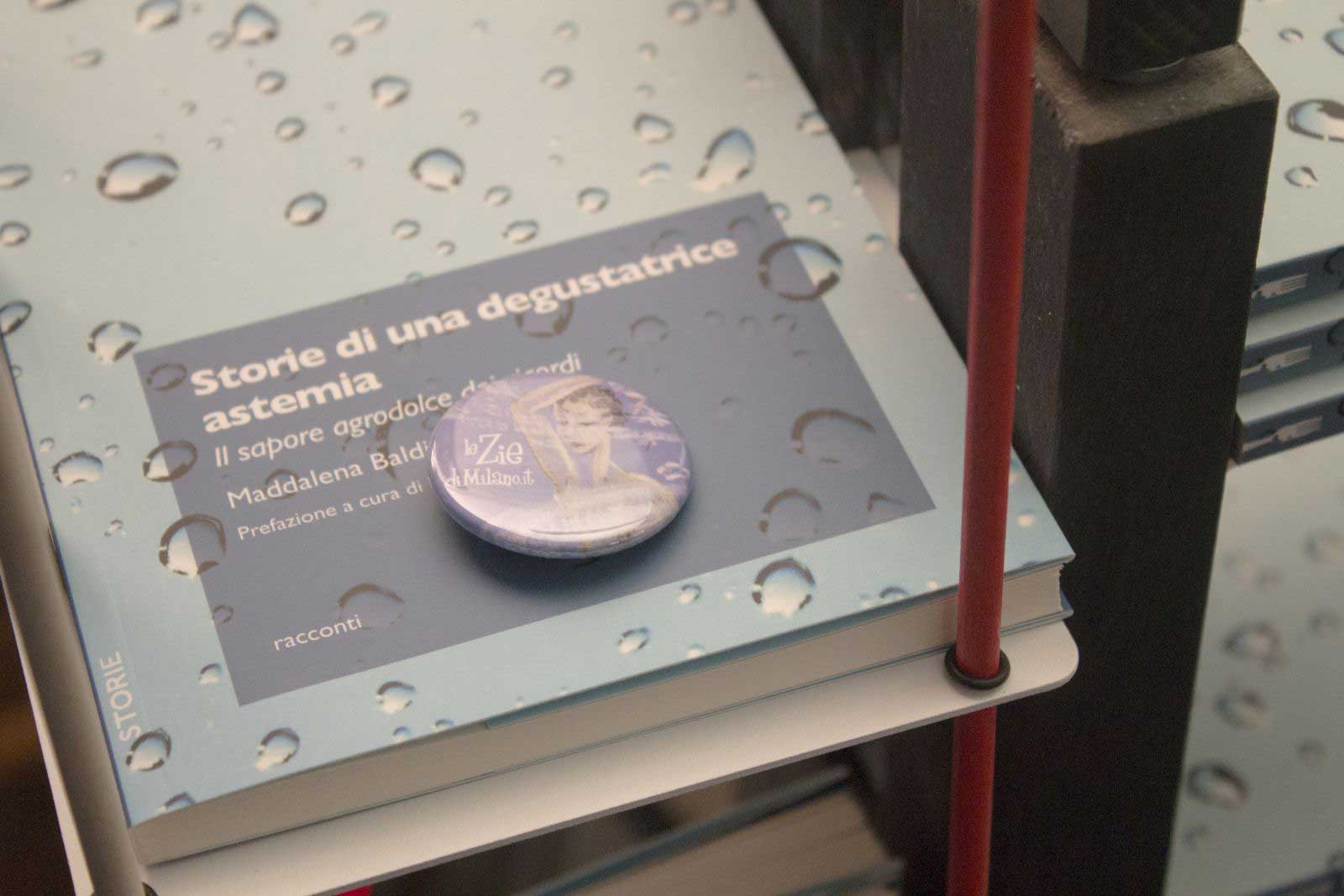 il libro "storie di una degustatrice astemia" su una libreria Zia Veronica, con una spilla de Le Zie di Milano
